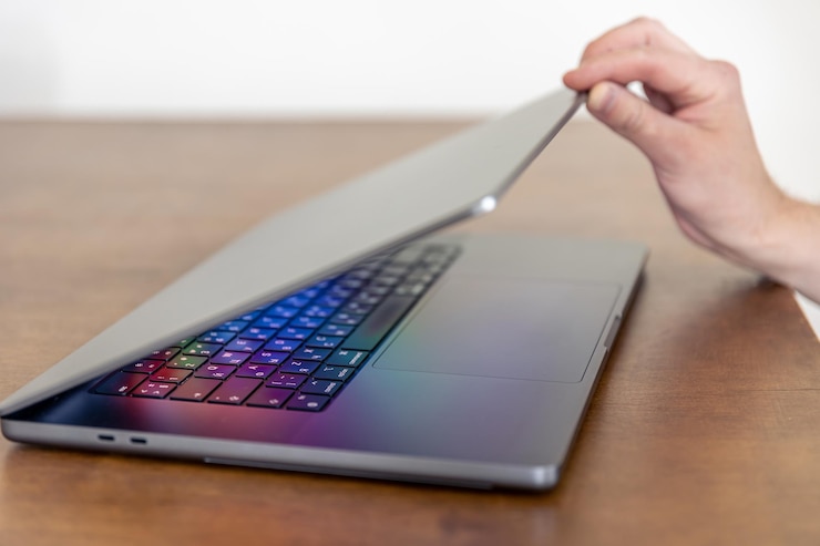 Foto la mano de un hombre abre una computadora portátil con una pantalla brillante multicolor
