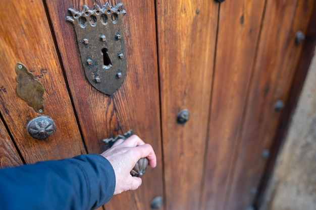 La mano del hombre abriendo una puerta de madera medieval en el casco antiguo de Pedraza Segovia España