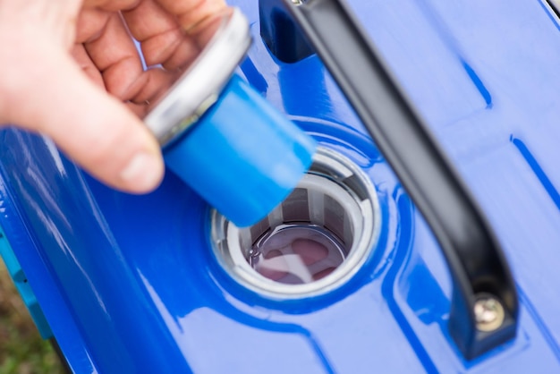 Foto mano de un hombre abriendo la tapa de un depósito de combustible del generador para rellenarlo