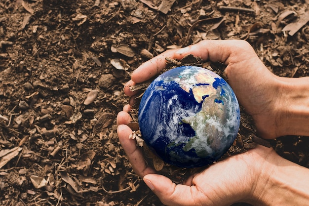 La mano del hombre agrícola sostenía un pequeño mundo azul en sus manos descansando en el suelo, Concepto del Día de la Tierra, Elementos de esta imagen proporcionados por la NASA.