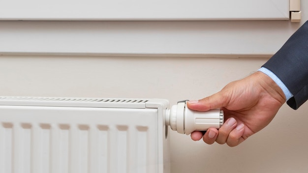 Mano del hombre ajustando la temperatura de un radiador