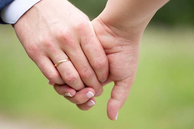 La mano de un hombre con un anillo de bodas sostiene la mano de una mujer.