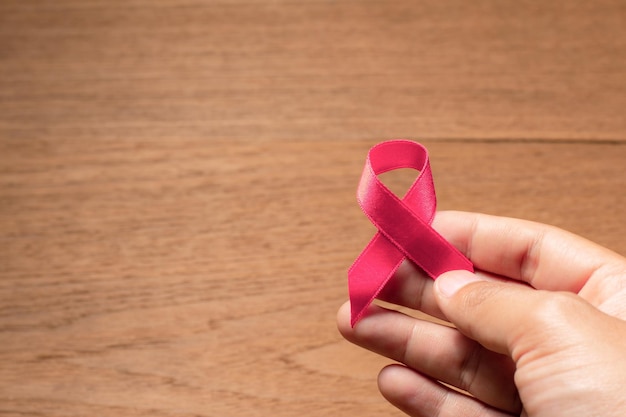 Mano de hombre con cinta rosa para la concientización sobre el cáncer de mama