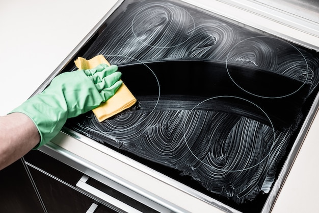 La mano del hombre en la cocina de limpieza guante verde en la cocina de casa