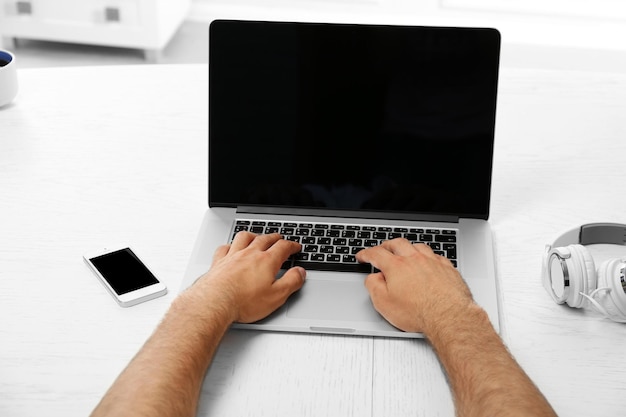Mano del hombre en la computadora portátil en la vista de la mesa