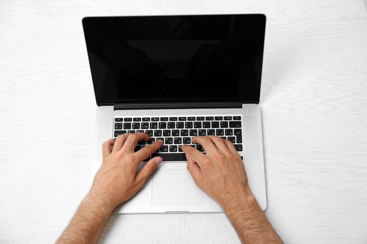 Foto mano del hombre en la computadora portátil en la vista de la mesa