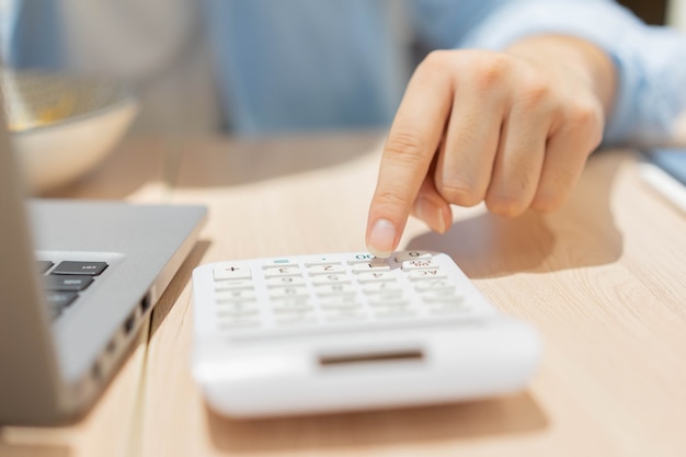 Mano de hombre de contabilidad presionando la calculadora para calcular el beneficio mensual del negocio