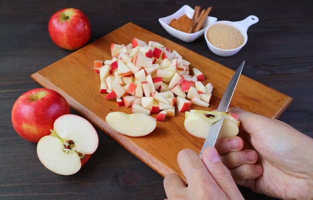 Mano del hombre cortando manzanas frescas con un cuchillo para hacer compota de manzana