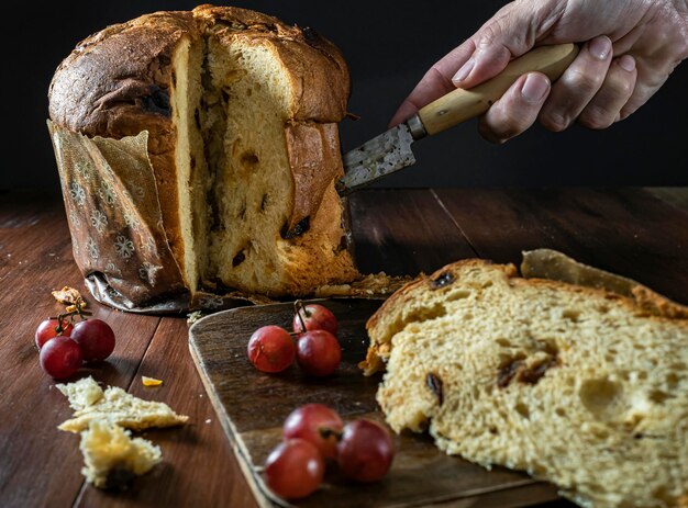 Mano de hombre cortando un trozo de Panettone Colores cálidos y ambiente navideño