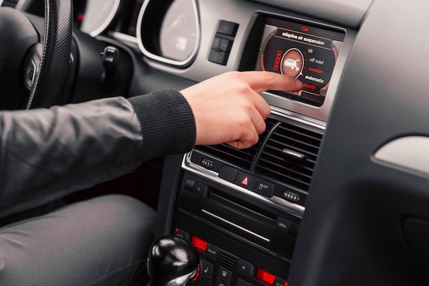 La mano del hombre elige el estilo de conducción en la computadora de a bordo del automóvil.