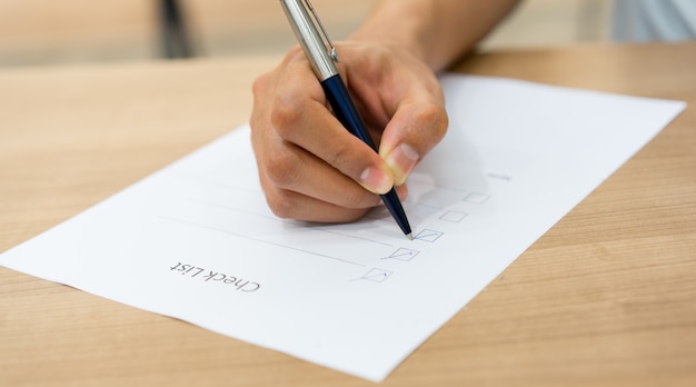 mano de hombre empleado usando pluma para verificar la lista