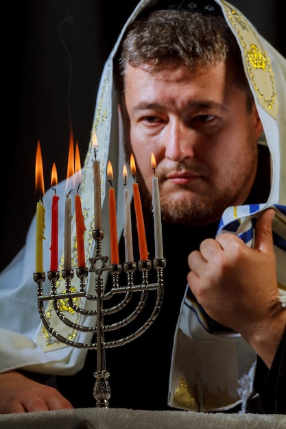 Mano de hombre encendiendo velas en menorah en mesa servida para Hanukkah