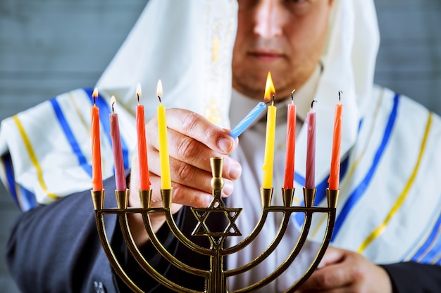 Mano de hombre encendiendo velas en menorah en mesa servida para Hanukkah