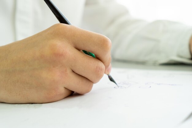 Foto la mano de un hombre escribe con una pluma estilográfica en un pedazo de papel notas de exámenes de concepto de regreso a la escuela