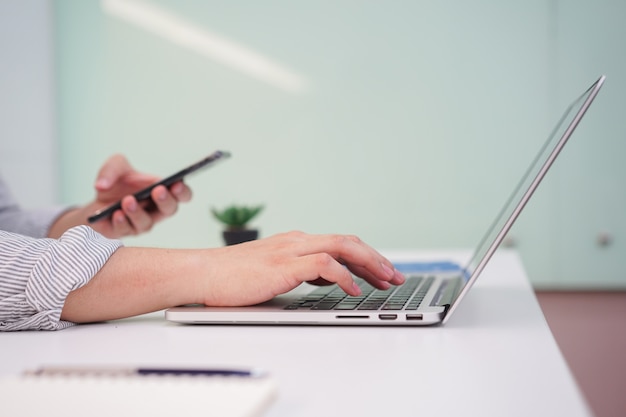 Mano de hombre escribiendo en dispositivo portátil de computadora de teclado en la habitación