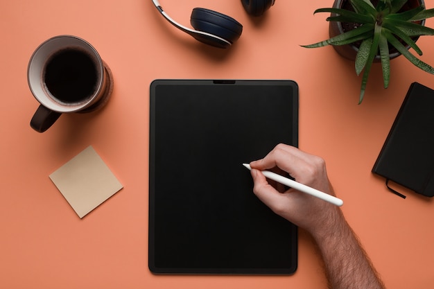 La mano de un hombre escribiendo en una tableta digital maqueta