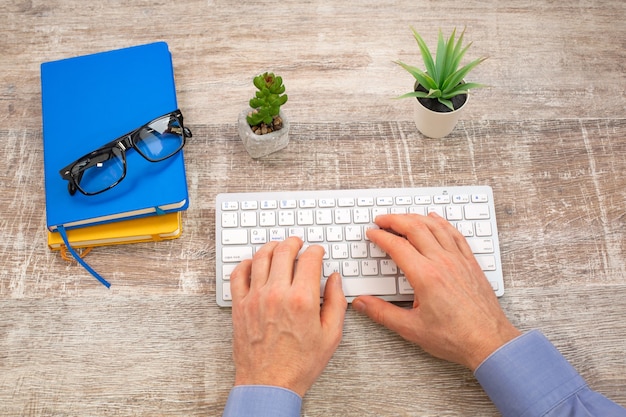 Mano de hombre escribiendo en el teclado blanco