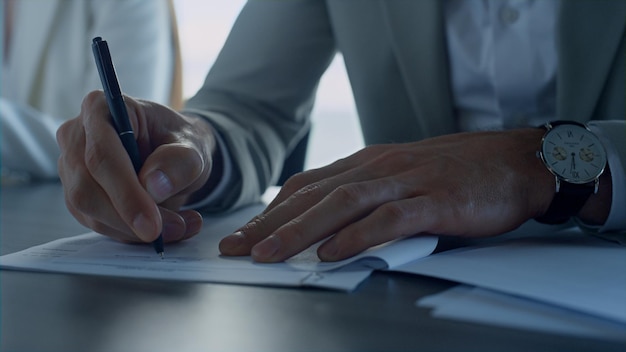 Mano de hombre firmando papeles en primer plano de la oficina Acuerdo de comprobación del cliente de seguros