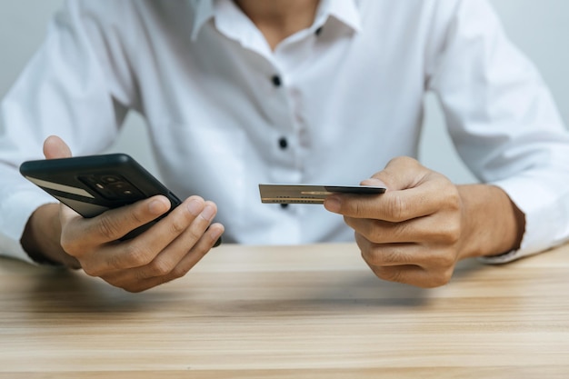 Mano de hombre ingresando el código de contraseña en el teléfono móvil pagando la factura con la factura de la tarjeta de crédito en el escritorio de la oficina en casa, Internet, marketing digital, banca móvil, pago en línea y concepto de tecnología digital