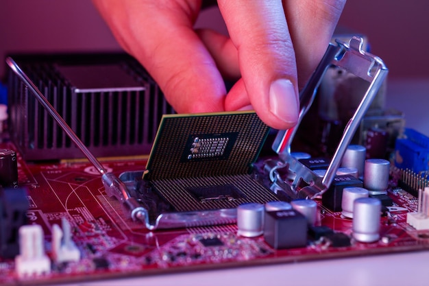 Foto la mano de un hombre inserta un procesador en el conjunto de chips de la placa base