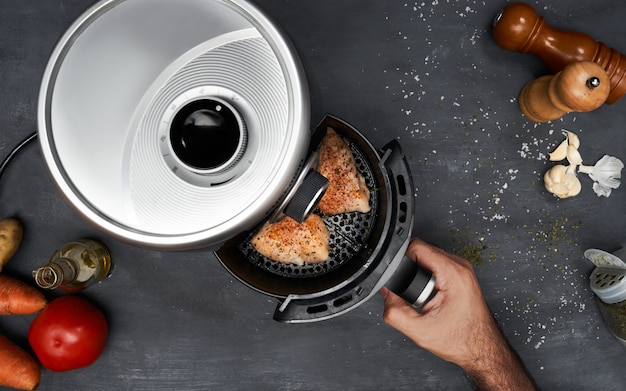 Foto mano de hombre irreconocible cocinar pechuga de pollo sin piel con especias en una freidora