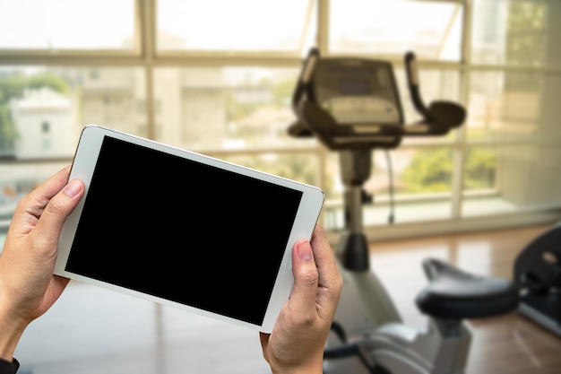 Mano de hombre joven que sostiene el teléfono inteligente en el gimnasio al concepto de ejercicio de fitness teléfono fitness