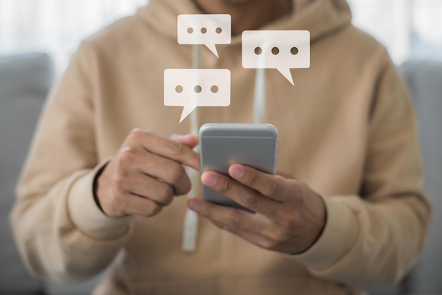 Mano de hombre joven sosteniendo y escribiendo en el teléfono inteligente chateando con un amigo en la aplicación.