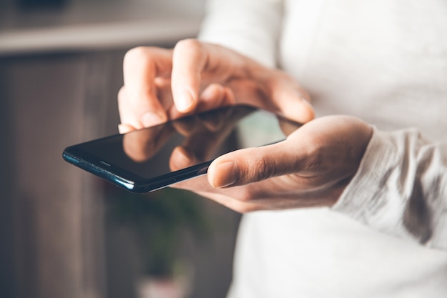 Mano de hombre joven sosteniendo teléfono inteligente