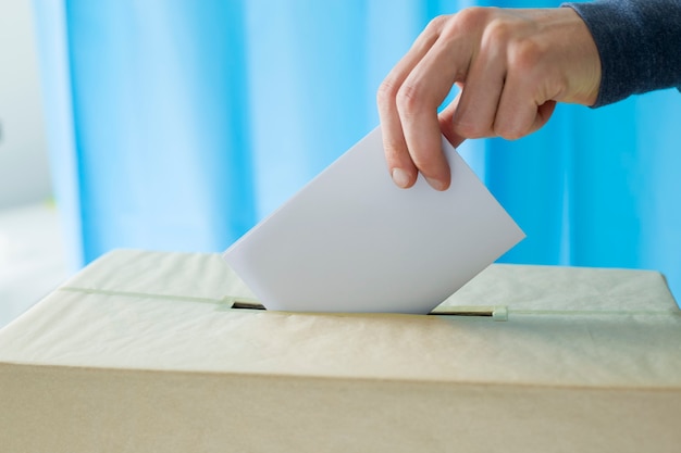 La mano del hombre lanza una papeleta para votar en un colegio electoral durante las elecciones.