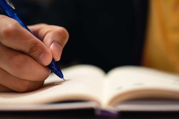 Mano de hombre con lápiz escribiendo en el cuaderno.