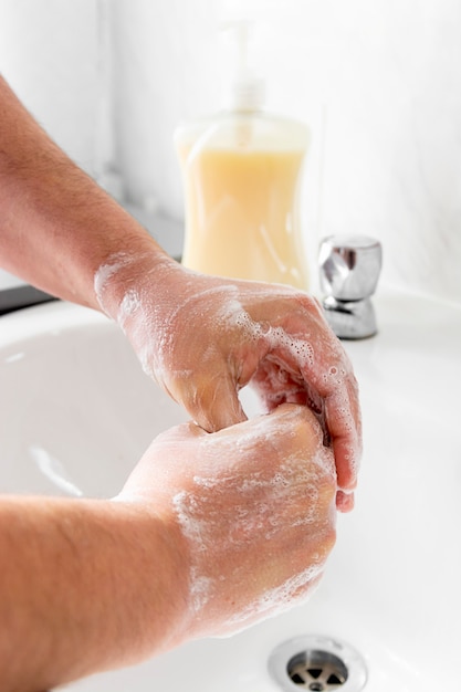 La mano del hombre se lava las manos sobre el lavabo en el baño.