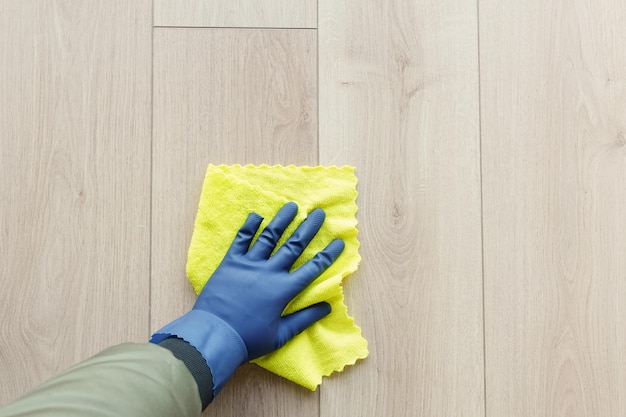 Una mano de hombre lavando el suelo con un paño