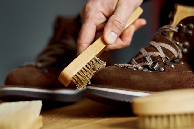 La mano del hombre limpia los zapatos de gamuza con un cepillo