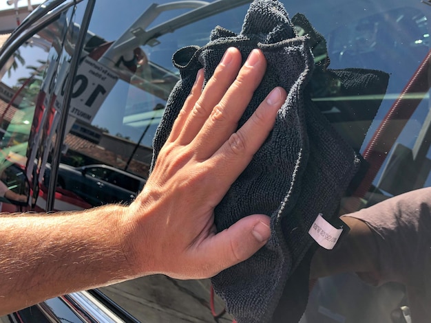 La mano del hombre limpiando el camión con un paño de microfibra negro. Limpiar a mano la superficie del coche.