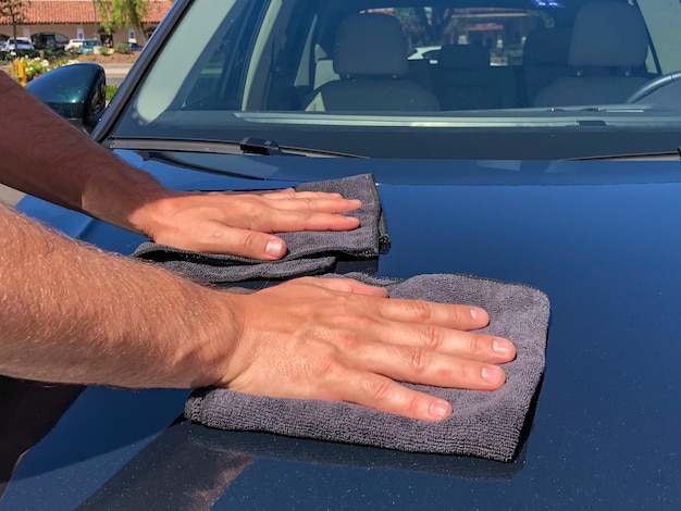 La mano del hombre limpiando el camión con un paño de microfibra negro. Limpiar a mano la superficie del coche.