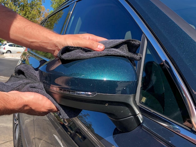 La mano del hombre limpiando el camión con un paño de microfibra negro. Limpiar a mano la superficie del coche.