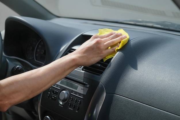 mano del hombre limpiando y limpiando con un paño el salpicadero del coche