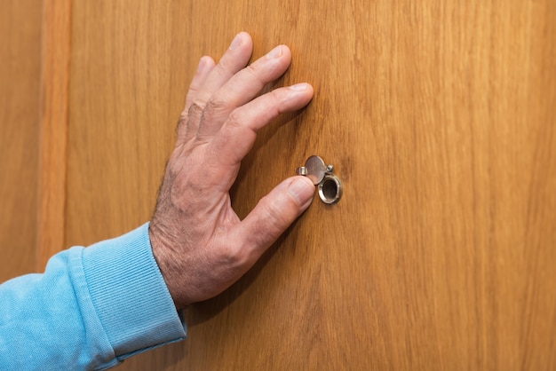 Foto la mano del hombre mayor abre la puerta de la mirilla