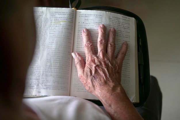 La mano del hombre mayor encima de un libro abierto