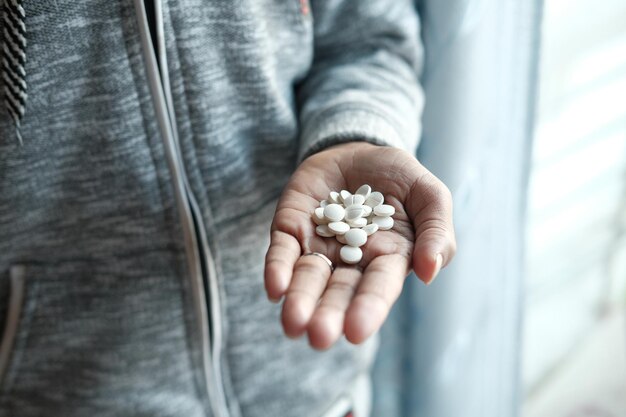 mano de hombre con medicina derramada del recipiente de pastillas