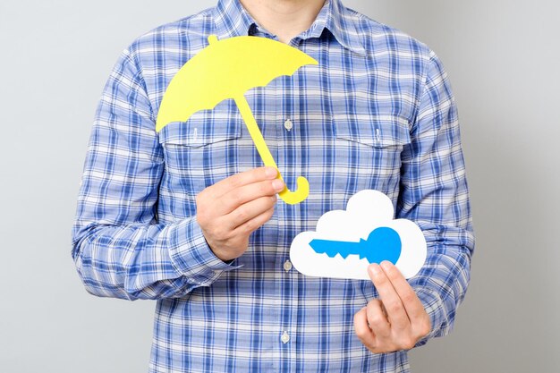 La mano del hombre con modelo de papel de nube y llave azul