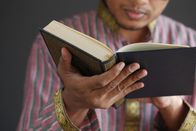 Mano de hombre musulmán sosteniendo el corán del libro sagrado con espacio de copia