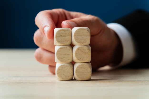 Mano de un hombre de negocios apilando dados de madera en blanco en una imagen conceptual