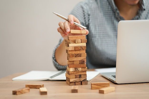 mano de hombre de negocios con bloque de madera para jugar torre creada