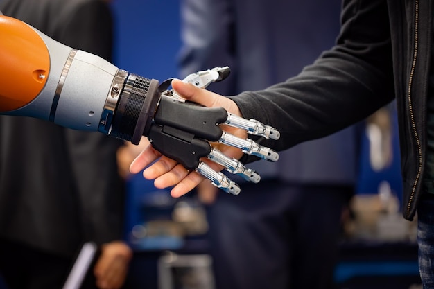 Mano de un hombre de negocios dándose la mano con un robot Android. El concepto de interacción humana con inteligencia artificial.