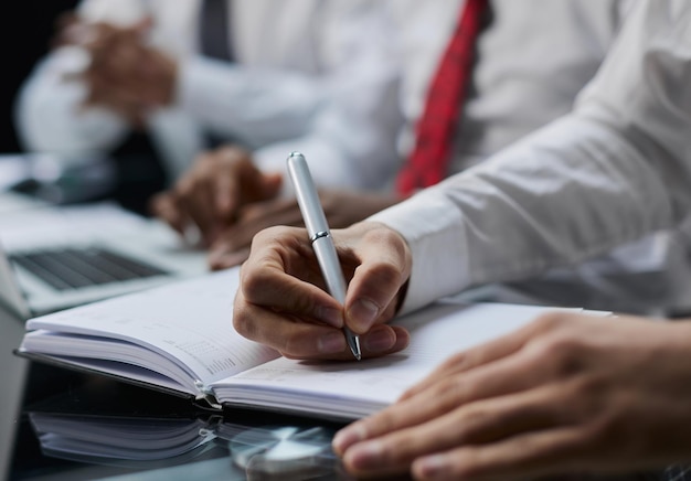 Mano de hombre de negocios escribiendo nota en un cuaderno hombre de negocios de primer plano que trabaja en el escritorio de la oficina