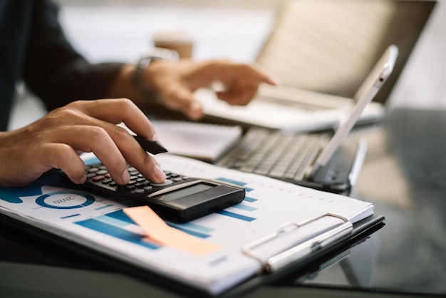 Mano de hombre de negocios haciendo finanzas y calculando en el escritorio sobre el costo en la oficina