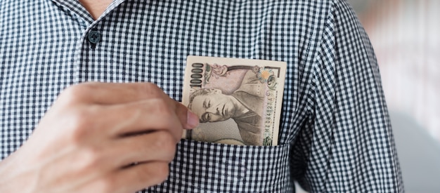 Mano de hombre de negocios con pila de billetes de Yen japonés. conceptos de negocios, dinero, inversión, finanzas y pagos