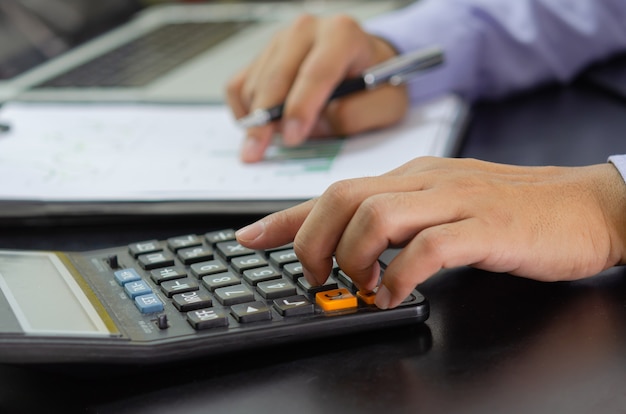 Mano de hombre de negocios presionando una calculadora Concepto de negocio, finanzas, impuestos e inversión.