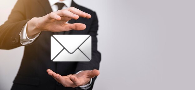 Mano de hombre de negocios que sostiene el icono de correo electrónico, contáctenos por correo electrónico del boletín y proteja su información personal del correo no deseado. centro de llamadas de servicio al cliente en contacto con nosotros concepto.